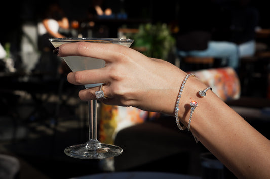 A hand holding a drink, with a ring and bracelets from Sapirion